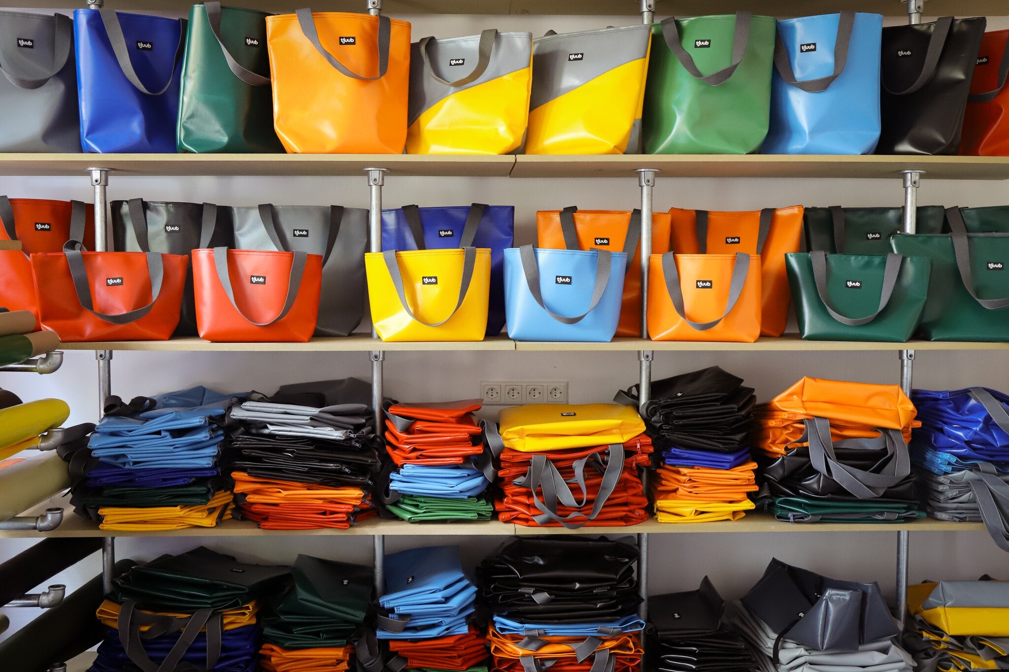 Volles Lagerregal mit tjuub Taschen in vielen Farben in der Manufaktur in Bayreuth.
