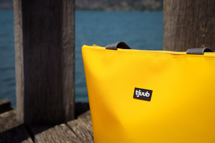 Nahaufnahme der gelben tjuub Tasche Lassen mit Markenlabel, Material recycelte LKW-Plane.