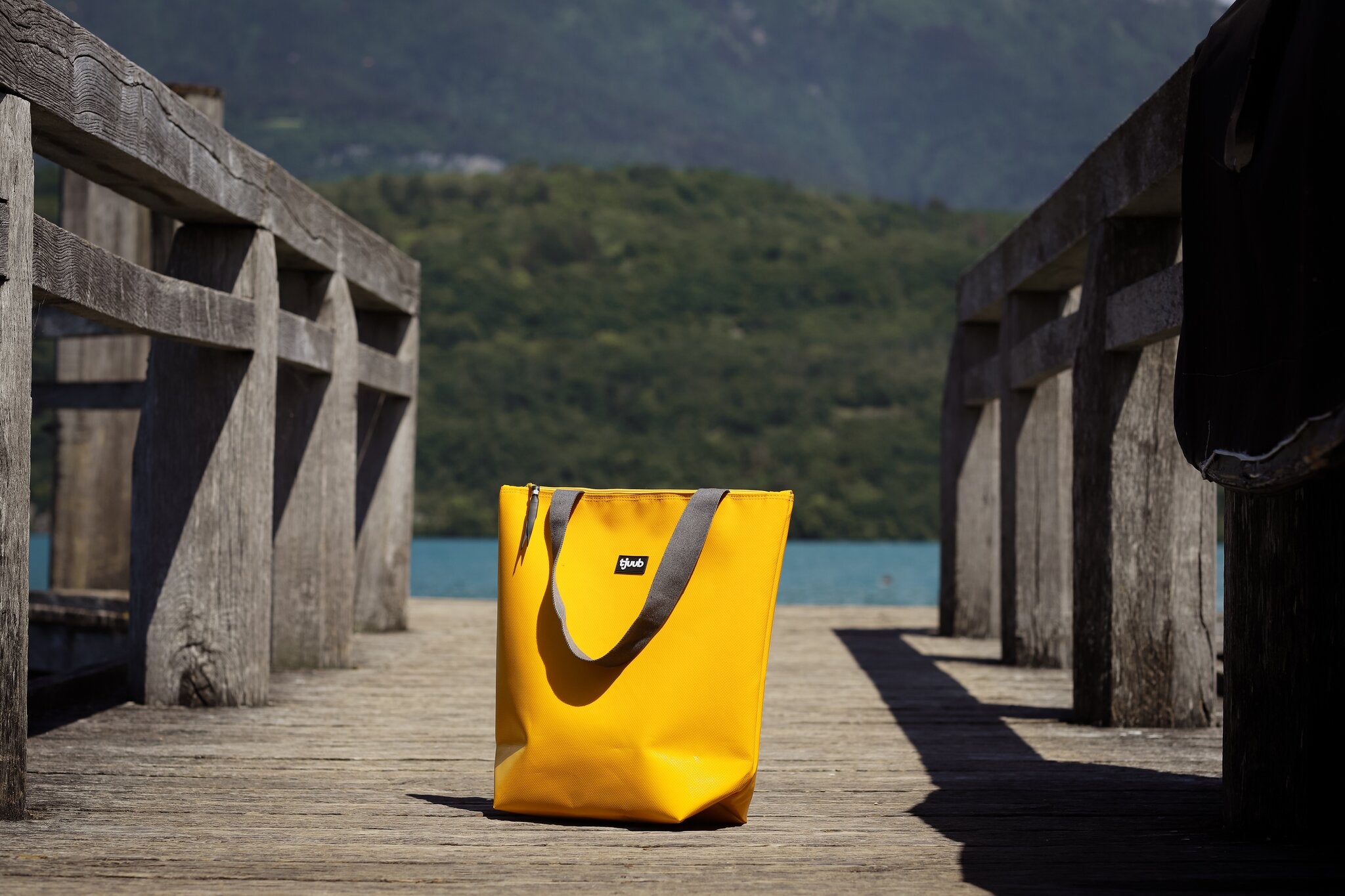 Gelbe tjuub Tasche Lassen steht allein auf einem Holzsteg am See.
