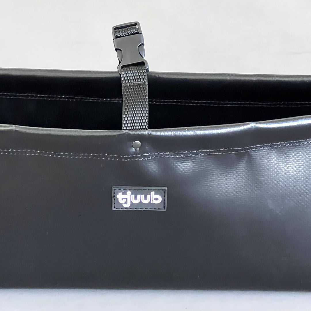 Nahaufnahme des dunkelgrauen Organizers Muddus aus LKW-Plane mit Steckschnalle und tjuub Label.