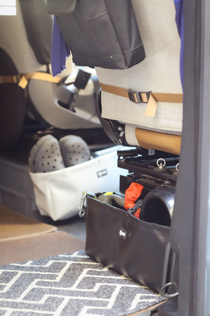 Schwarze tjuub Tasche Muddus unter dem Fahrzeugsitz im Camper, Stauraumlösung für Vanlife.