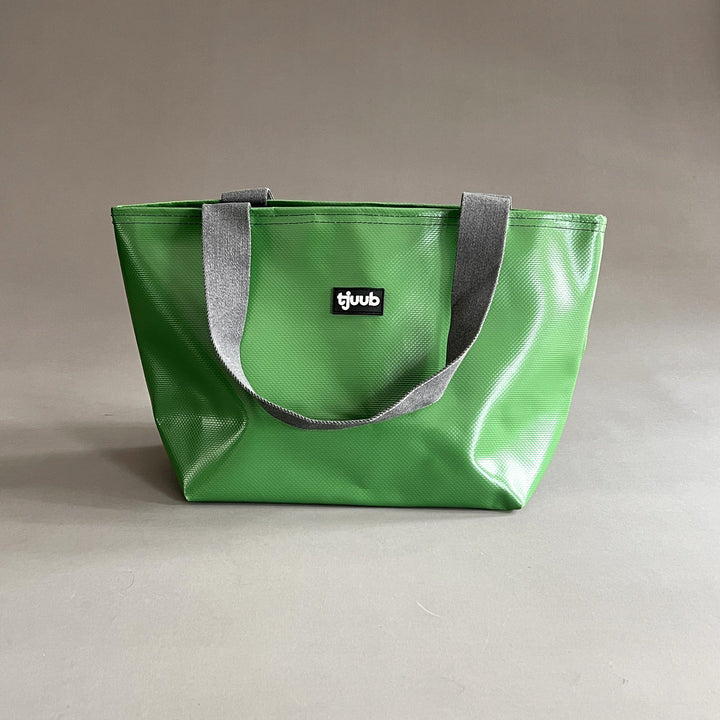 Kleine Tasche Sila in Grasgrün aus recycelter LKW-Plane mit Reißverschluss, Seitenansicht mit grauen Gurtbandträgern.
