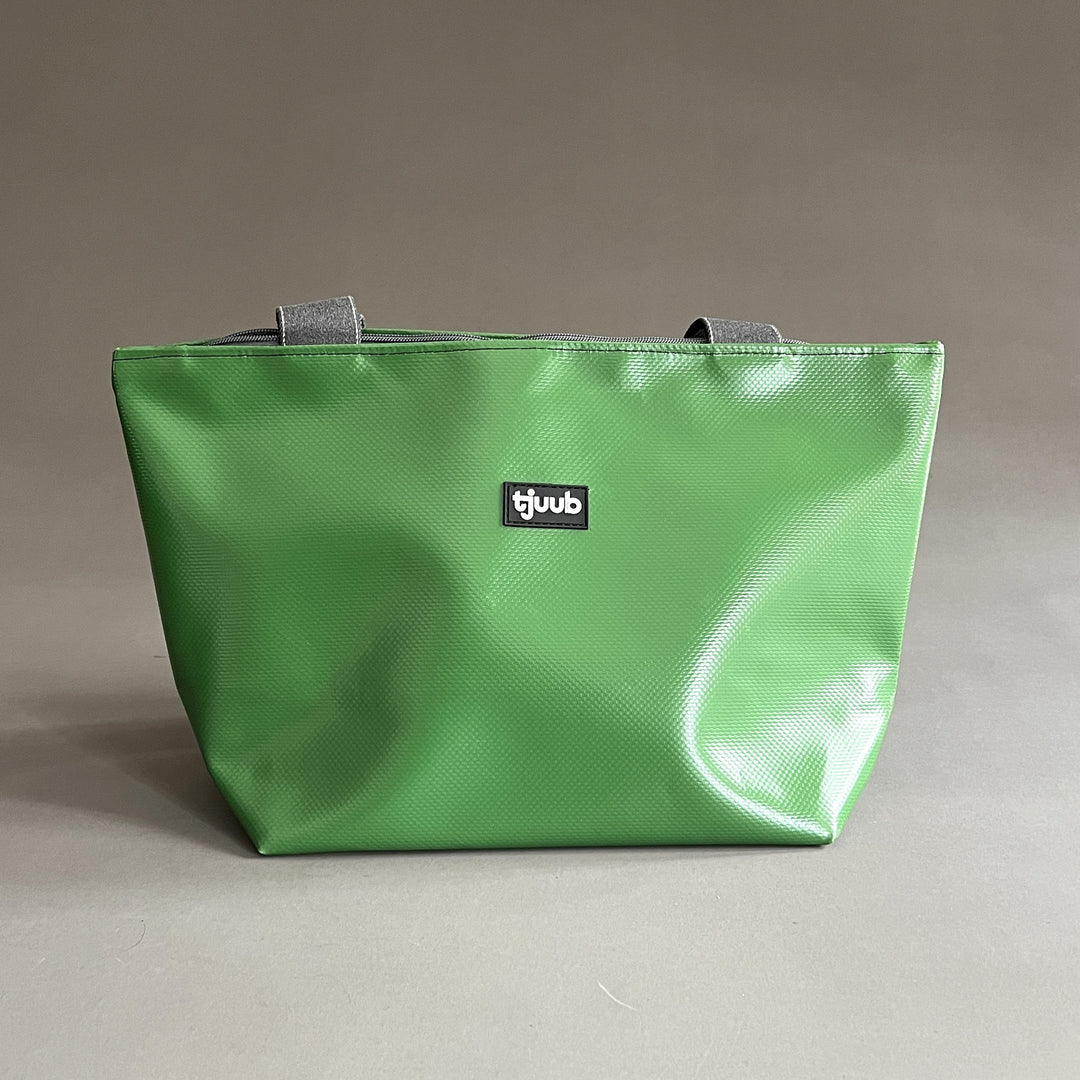 Kleine Tasche Sila in Grasgrün aus recycelter LKW-Plane ohne Reißverschluss, mit grauen Trageriemen.