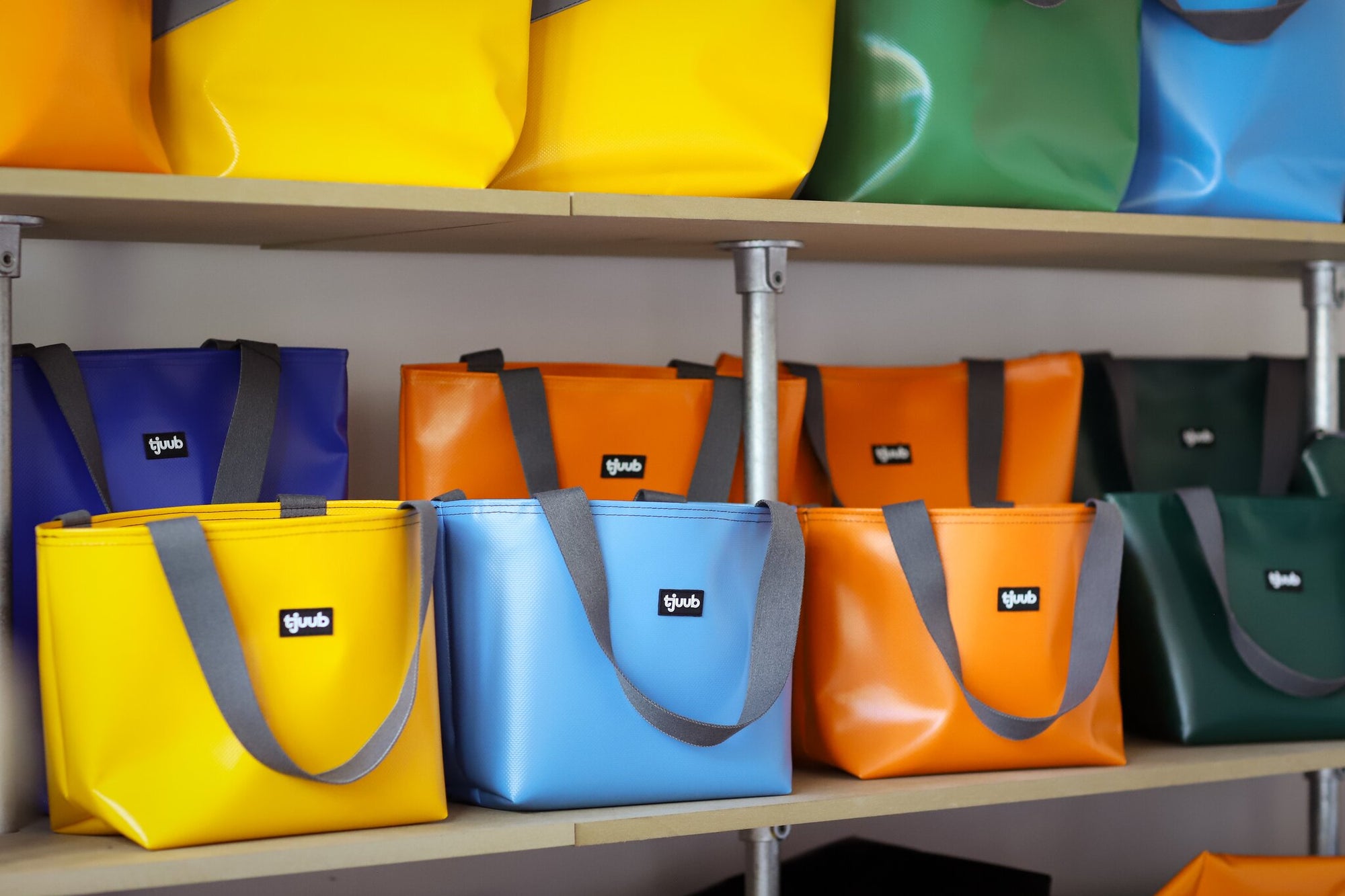 Fertige tjuub Taschen aus LKW-Plane im Regal - Farbauswahl Gelb, Hellblau, Orange