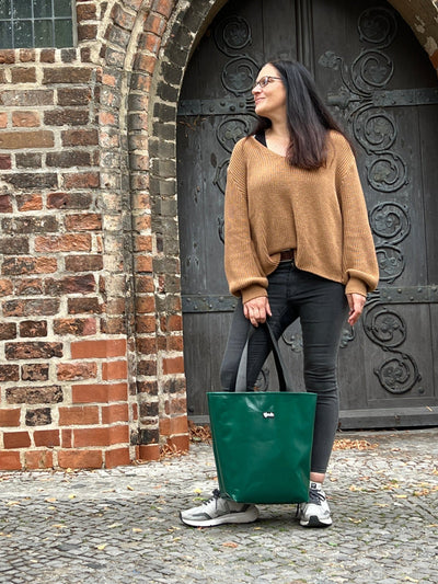 Das Bild zeigt Dagmar, die Gründerin des Upcycling Taschen Labels tjuub mit einer grünen Tasche aus LKW Plane in der Hand