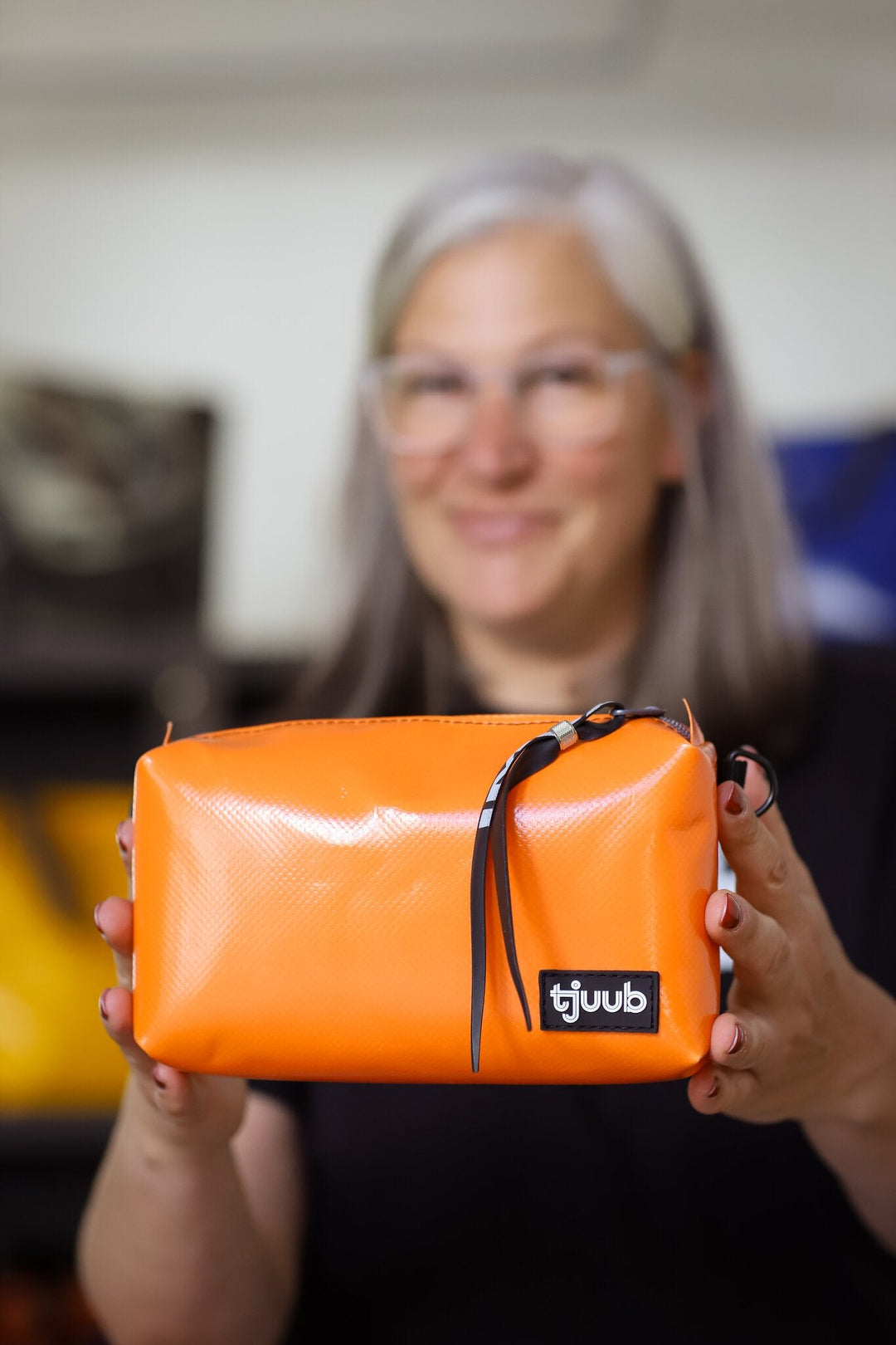 Fertige orange tjuub Umhängetasche Una aus recycelter LKW-Plane in den Händen der Gründerin.