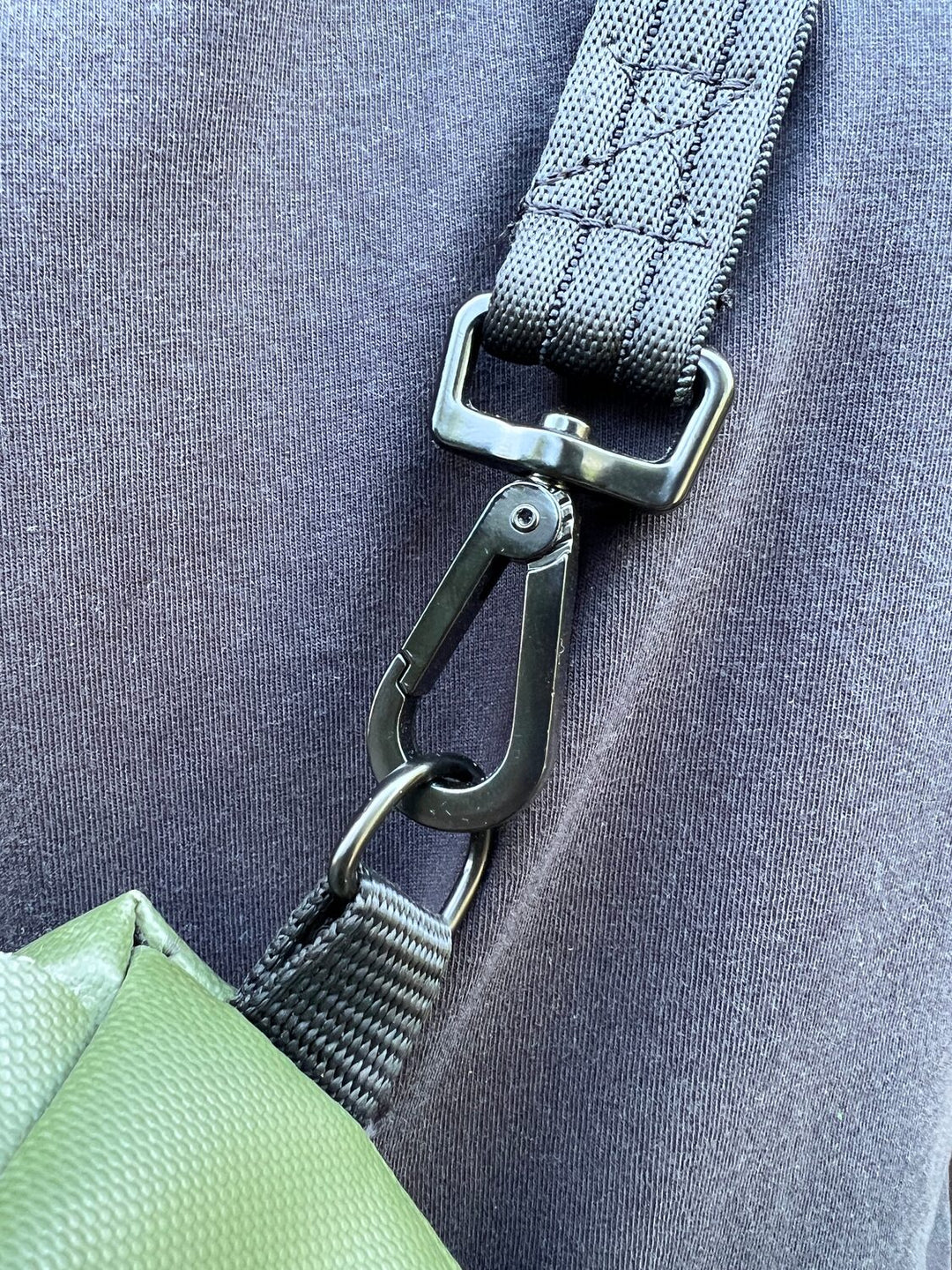 Detailaufnahme des schwarzen Karabiners am grauen Trageriemen der olivgrünen Umhängetasche Una von tjuub.