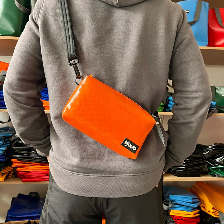 Una kleine Umhängetasche aus LKW-Plane in Orange als Crossbody von hinten getragen, vegan und unisex